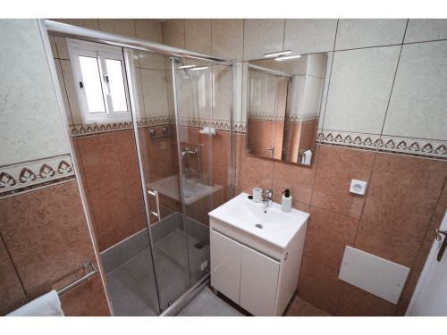 Cuarto de baño moderno en la villa SpecialStays Atlantic Escape de Funchal con paredes alicatadas, ducha con mampara de cristal y tocador blanco