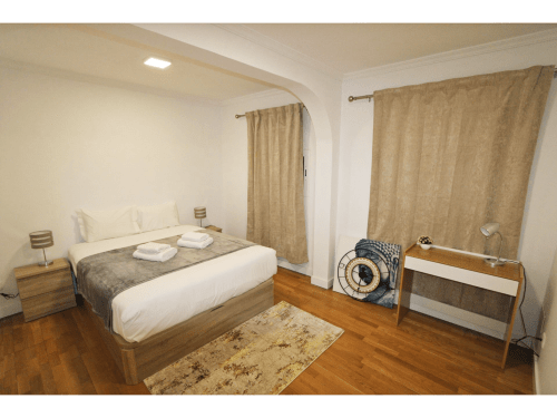 Dormitorio moderno en villa Atlantic Escape, Funchal con cama de madera, cortinas con vistas al mar y piso de madera