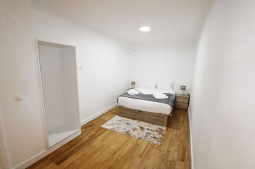 Dormitorio luminoso en la villa Atlantic Escape, Funchal con cama de madera, paredes blancas, suelo de madera y iluminación moderna