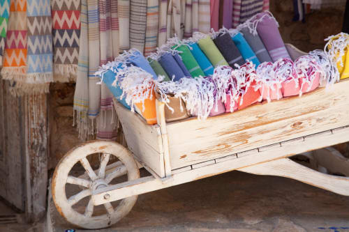 Textiles colorés enroulés et tissus exposés sur chariot en bois au Riad Eucalyptus à El Ghazouane, Maroc