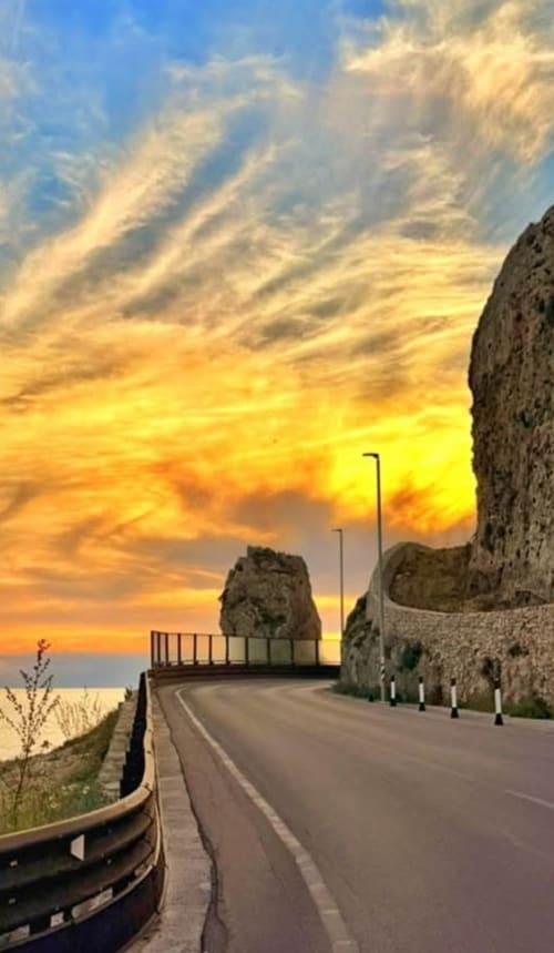 Strada costiera al tramonto vicino a Gallipoli con scogliere drammatiche e vista sul mare presso Le Case di Esteca