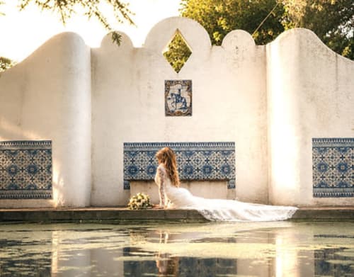 Noiva em vestido branco com cauda posando no pátio português com azulejos azuis e brancos da Quinta do Carril