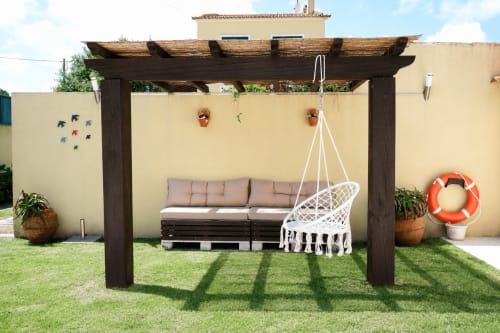 Dark wooden pergola with white hammock chair and patio seating in garden at Be SilverCoast hotel villa