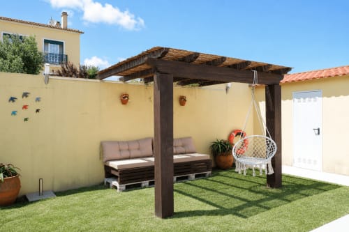 Peaceful garden patio at Be SilverCoast villa with wooden pergola, seating, and white hanging chair