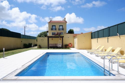 Private pool with lounge chairs at Be SilverCoast villa in Serra D'El Rei, Portugal, yellow walls and blue water