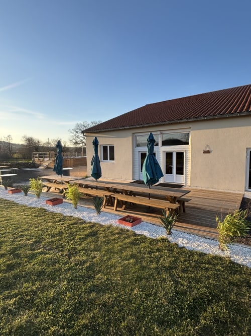 Terrasse du gîte Mas De Bannayoux avec deck bois, parasols bleus, chaises longues et vue sur les montagnes à Couteuges