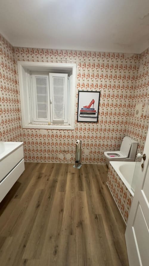 Banheiro moderno da Pink-Shell B&B com papel de parede vermelho estampado, vaso sanitário, pia e quadro de arte de salto vermelho