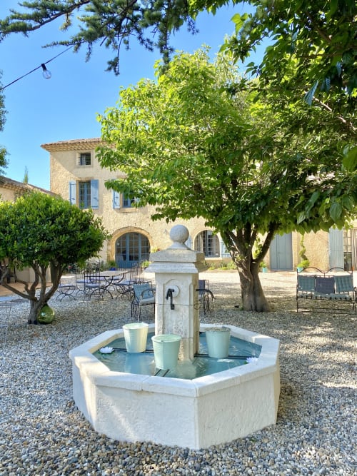 Cour en pierre rustique avec fontaine centrale au gîte Le Mas de la Soie à Violes, France