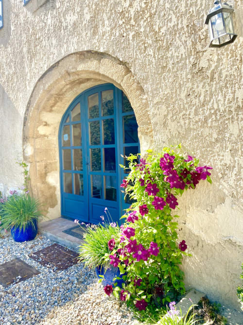 Porte bleue en arc avec fleurs magenta éclatantes au Mas de la Soie B&B à Violes, France