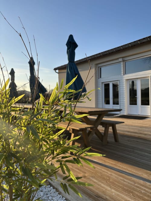 Terrasse de la salle de réception du Mas De Bannayoux avec terrasse bois, parasol, plantes décoratives et vue sur les montagnes à Couteuges