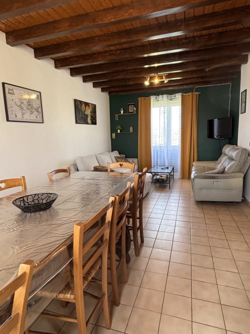 Séjour et salle à manger ouverts au Mas De Bannayoux avec poutres en bois, table de repas, mobilier confortable et accent vert