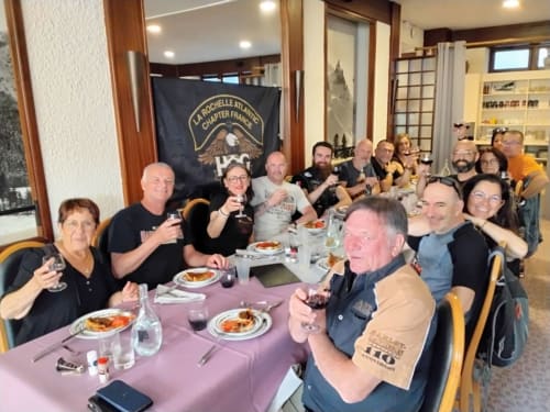 Groupe réuni à l'Hôtel Aviation à La Bourboule savourant un dîner avec du vin à une table de banquet