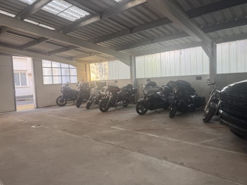 Parking motos du Hôtel Aviation à La Bourboule avec plusieurs motos et toit en tôle ondulée