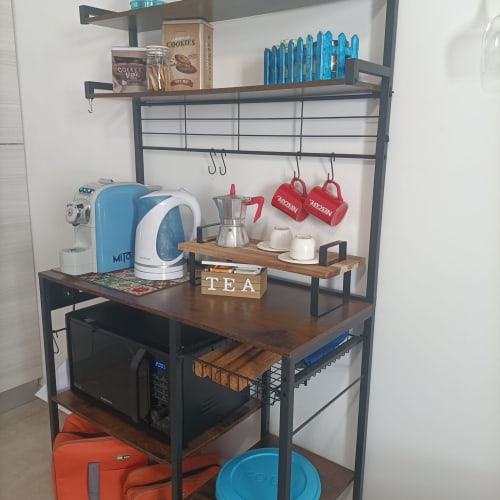 Angolo caffetteria in cucina con moka blu, macchina da caffè, tazze rosse e accessori da tè presso l'appartamento Le Case di Esteca.