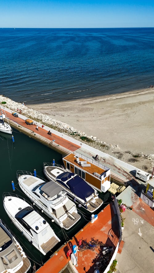 Barche ormeggiate e casa galleggiante alla marina di Cesena con spiaggia sabbiosa e mare blu cristallino