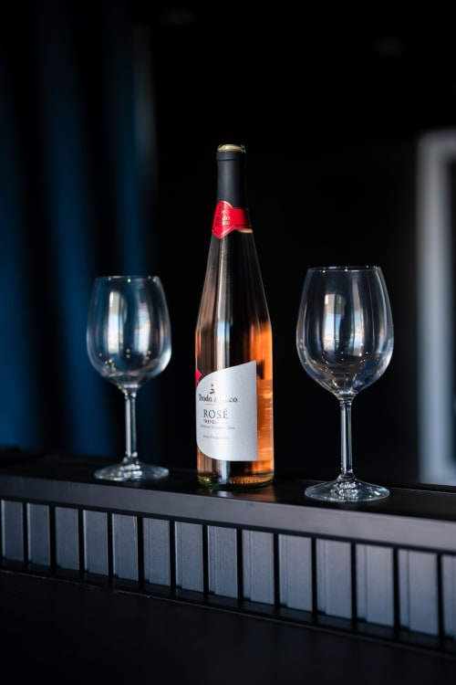 Bottiglia di vino rosé con due bicchieri vuoti su un bancone scuro al BHE House Boat apartment a Cesena