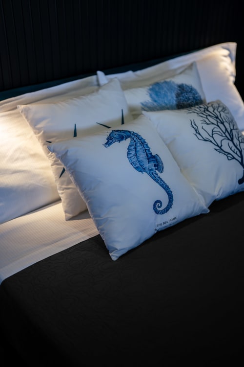 Cuscini decorativi a forma di cavalluccio marino su biancheria bianca nell'appartamento BHE House Boat Experience, Cesena