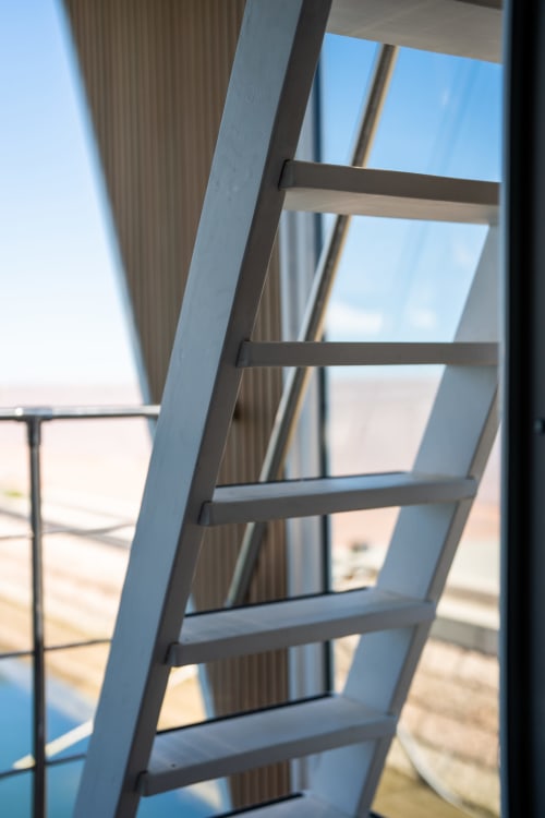 Moderna scala in metallo con gradini che salgono verso l'alto, vista sul mare attraverso le finestre dell'appartamento nella houseboat di LHE S.r.l a Cesena,