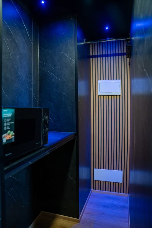 Corridoio moderno dell'appartamento BHE House Boat Experience a Cesena, con pareti in marmo blu, porta in listelli di legno e illuminazione ambientale
