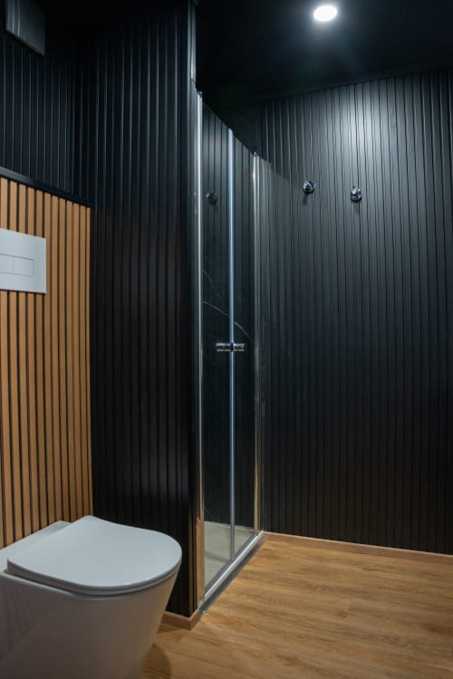 Bagno moderno nell'appartamento BHE House Boat Experience di Cesena con pareti corrugate nere, doccia aperta e wc bianco