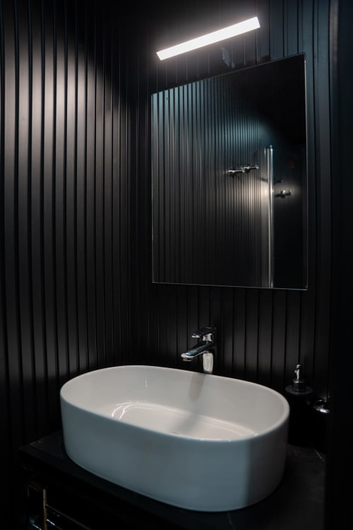 Bagno moderno in BHE House Boat Experience con vasca ovale bianca, pannelli murali neri, specchio illuminato e design contemporaneo