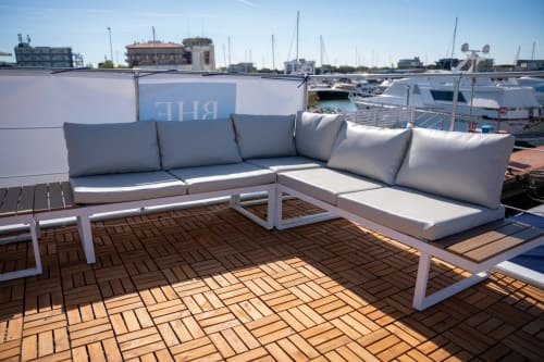 Moderna zona lounge con cuscini grigi su terrazza in legno affacciata sulla marina di Cesena, Italia