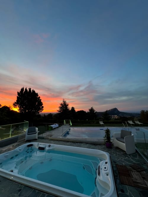 Luxuriöser Whirlpool bei Sonnenuntergang mit Blick auf Monte Grimano Terme, beleuchteter Pool und Bergpanorama