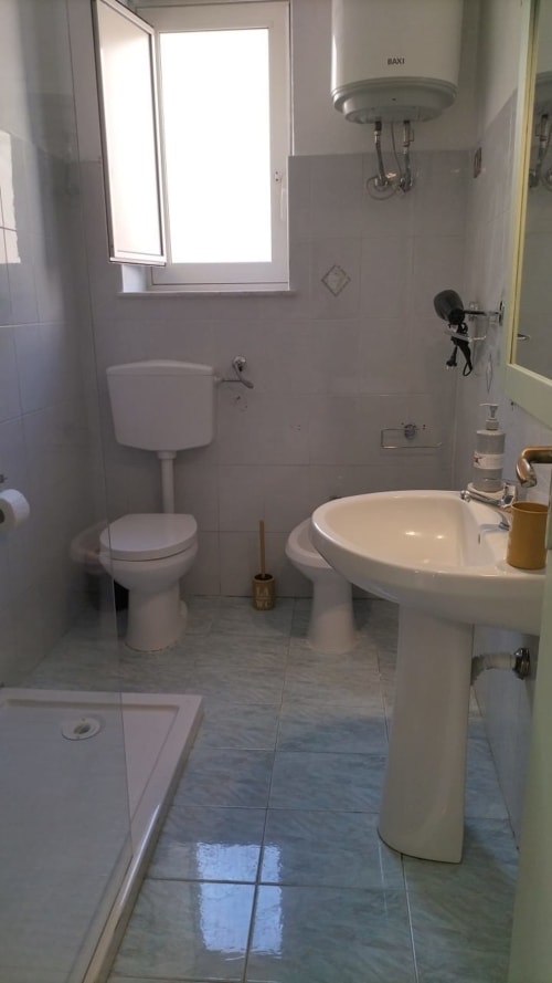 Bagno moderno della BnB Mappamondi a Venezia con lavabo su piedistallo, WC, finestra e scaldabagno Baxi