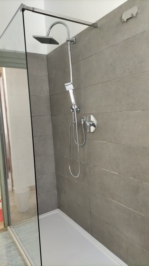 Moderna cabina doccia con rivestimento in piastrelle grigie e soffione pioggia presso la Mappamondi B&B di Venezia