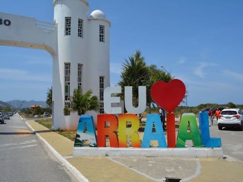 Placa colorida "I Love Arraial" com edifício torre branco na pousada Rio Vibes em Arraial do Cabo, Brasil