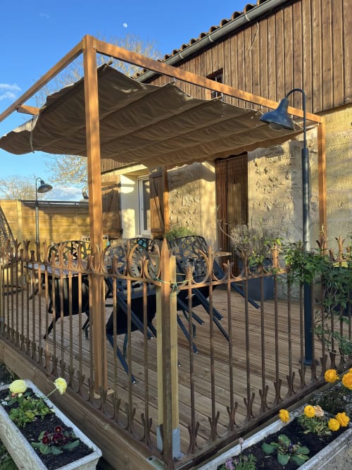 Pergola en bois avec store rétractable couvrant une terrasse de salle à manger des Chambres Et Gîte Peyroutas