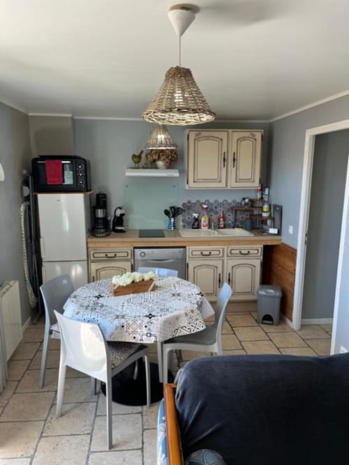 Cuisine et salle à manger chaleureuses du gîte Suzon avec table ronde, suspension tissée et armoires crème