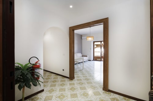 Elegante ingresso alla suite Profumo di Mare di ViOletta Roma, porta in legno che conduce a uno spazio living con vista sul mare