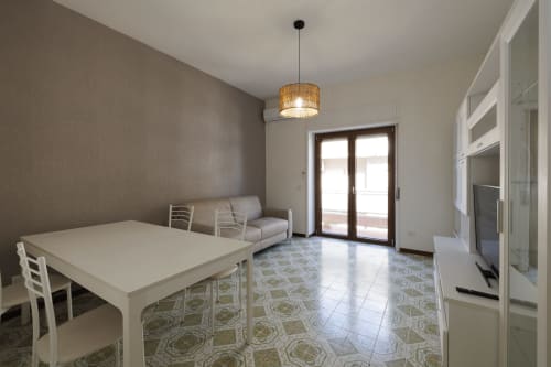 Zona pranzo dell'appartamento con vista mare al ViOletta hotel di Roma: tavolo bianco, sedie, divano grigio e balcone