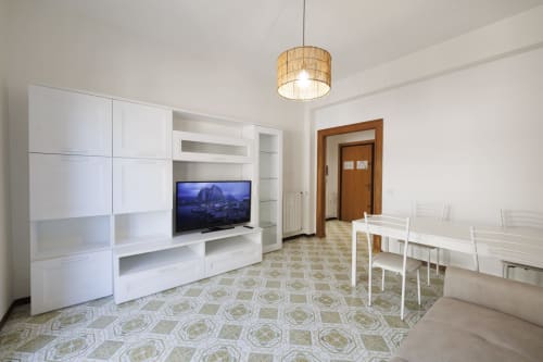 Soggiorno moderno dell'appartamento vista mare di ViOletta a Roma con mobile TV bianco, televisore schermo piatto, zona pranzo e
