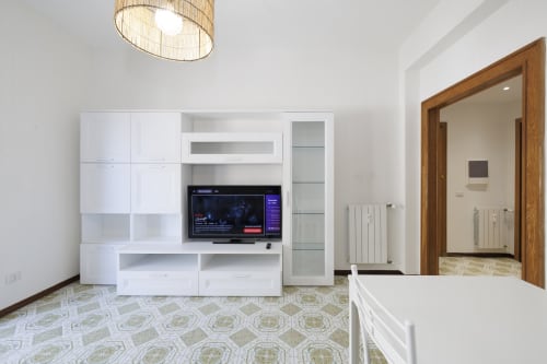 Soggiorno moderno dell'appartamento ViOletta Roma con arredamento bianco, TV a schermo piatto e pavimento a motivi geometrici