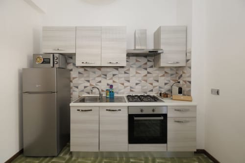 Cucina moderna nell'appartamento Profumo di Mare di ViOletta, Roma, con mobili in legno chiaro, piano cottura a gas e rivestimento geometrico