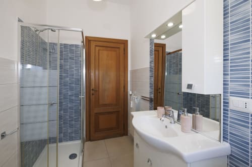 Bagno moderno nell'appartamento Profumo di Mare di ViOletta, Roma, con doppio lavabo, dettagli in piastrelle blu e doccia in cristallo