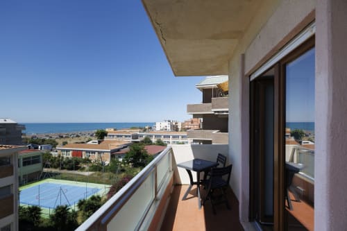 Balcone con vista mare dell'appartamento Profumo di Mare a ViOletta Roma con tavolo, sedia, spiaggia e costa mediterranea