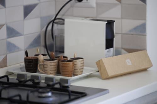 Tazze di caffè con branding espresso e imballaggi in cartone su scrivania bianca nell'appartamento Profumo di Mare di ViOletta, Roma