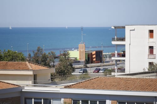 Vista mare dall'appartamento ViOletta a Roma con barche a vela, costa mediterranea e moderni edifici con balconate