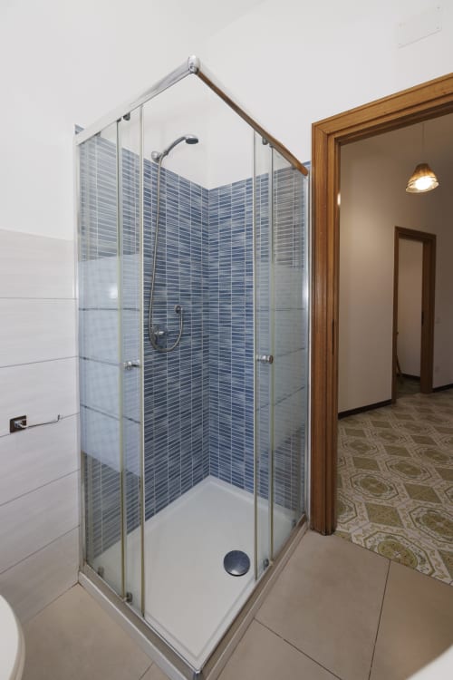 Moderna cabina doccia in vetro con parete in piastrelle blu nel bagno dell'apartamento ViOletta con vista mare, Roma