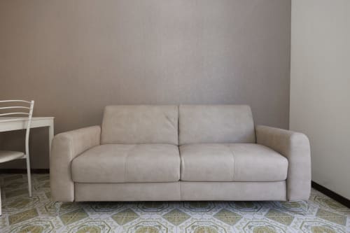 Divano beige in soggiorno moderno dell'appartamento ViOletta Roma con pavimento a motivi geometrici