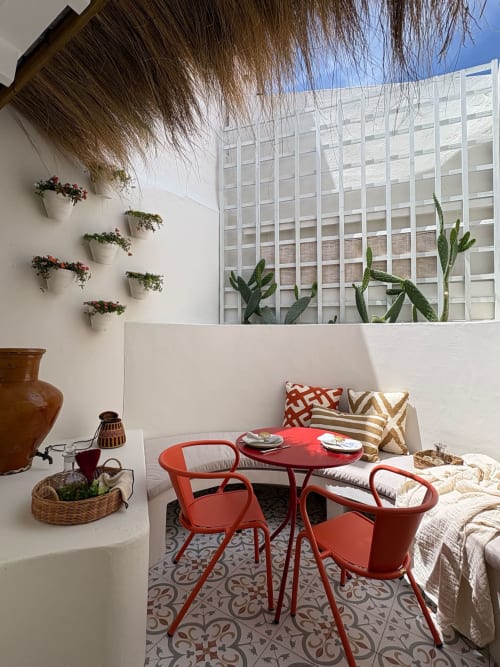 Terraço do apartamento Casa Fataca na Casa Amanhada, Grândola: cadeiras vermelhas, mesa redonda, paredes brancas, plantas em vasos, vista da cidade