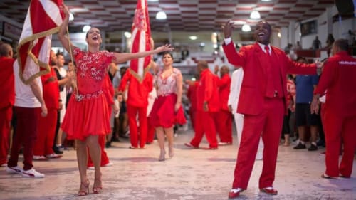 Hóspedes em trajes vermelhos celebram na Pousada Rio Vibes com bandeiras brasileiras durante um evento festivo no Rio de Janeiro