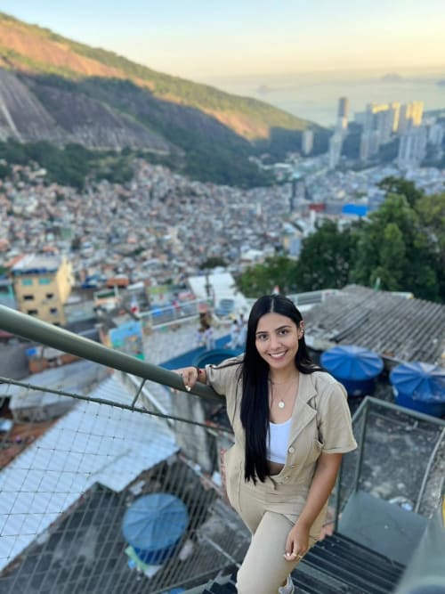 Mulher sorrindo na varanda do Rio Vibes Hostel com vista da cidade, montanhas e Rio de Janeiro ao fundo