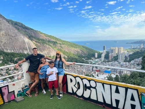Família no mirante da Pousada Rio Vibes com vista para o Rio de Janeiro, montanhas e oceano com parede de graffiti colorida