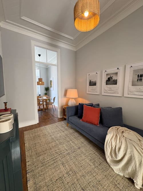 Sala de estar moderna no apartamento Casa Amanhada em Grândola com sofá escuro, luminária de teto em madeira e quadros na parede.