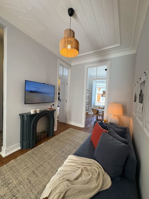 Sala de estar moderna em Casa Amanhada com sofá escuro, luminária de madeira, TV, lareira e vista para a cidade