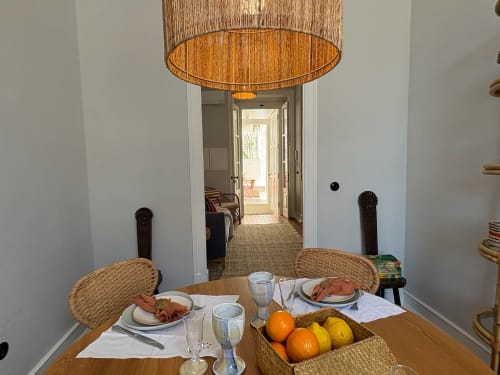 Sala de refeições da Casa Fataca em Grândola com mesa posta, cadeiras de vime, frutas cítricas e vista do corredor